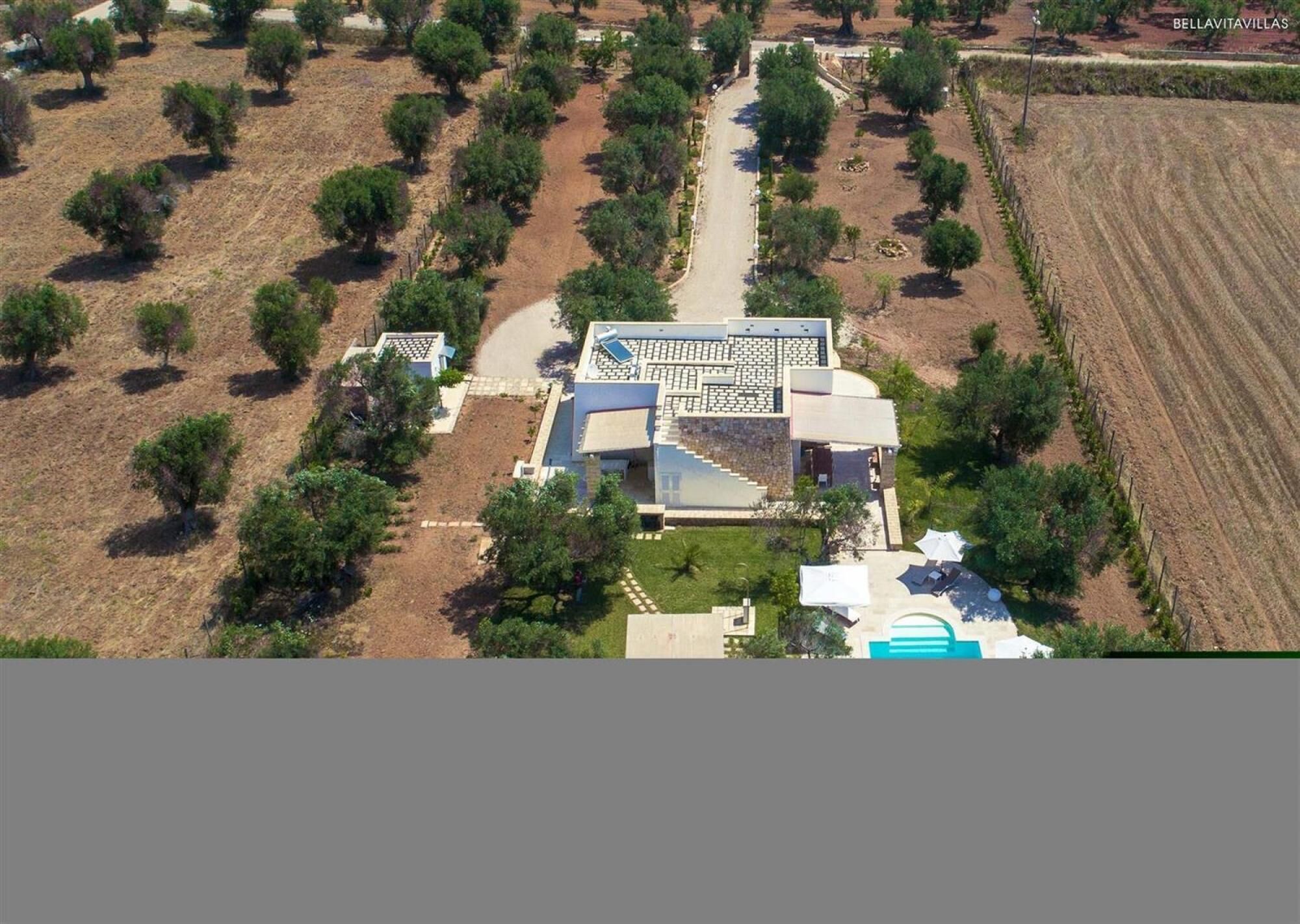 An aerial view of a property with a central building, surrounded by landscaped areas and fields.