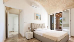 A bedroom with a bed, nightstand, and a painting on the wall. - 496 La Serrazza in Pescoluse Posto Vecchio (Salve)