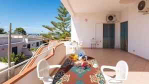A balcony with a table set for two, a small sink, and an air conditioning unit. - 1186 VPS Trilo PP 1 in Posto Rosso (Alliste)