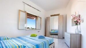 A bedroom with a bed, a bedside table, a mirror, and a wardrobe. - 1186 VPS Trilo PP 1 in Posto Rosso (Alliste)