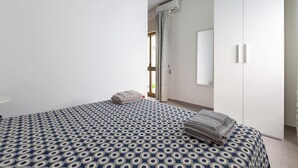 A bedroom with a bed, a wardrobe, a window, and an air conditioning unit. - 1298 Versomare - Monolocale Lu Ientu (Porto Cesareo)