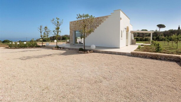 Un edificio moderno con un diseño escalonado distintivo, un camino de grava y una vista despejada del paisaje circundante.