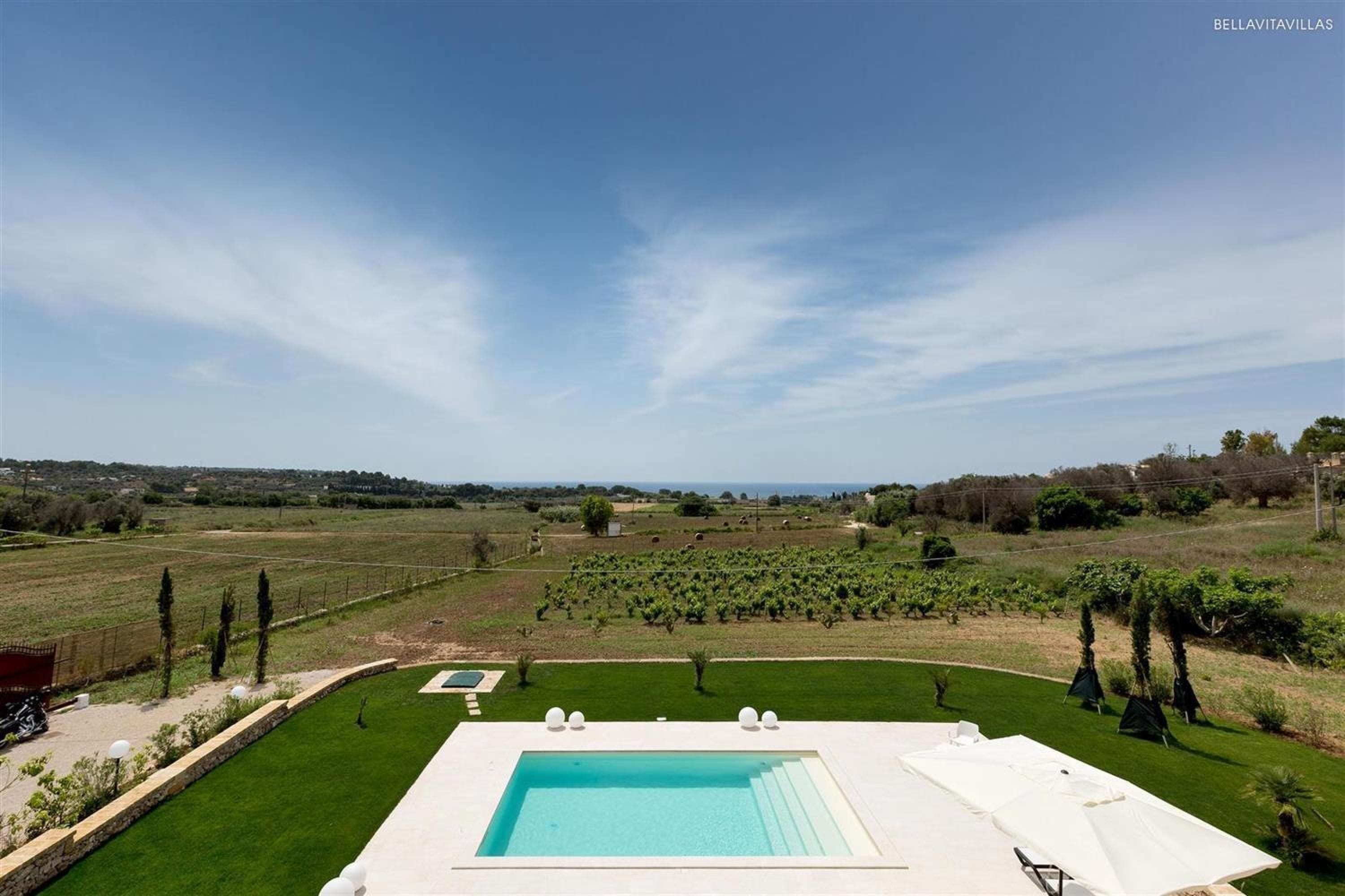 Une piscine offrant une vue dégagée sur le paysage environnant, notamment sur un vignoble et des collines lointaines.