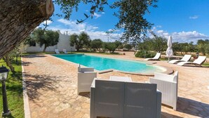 A swimming pool with lounge chairs and a stone pathway.