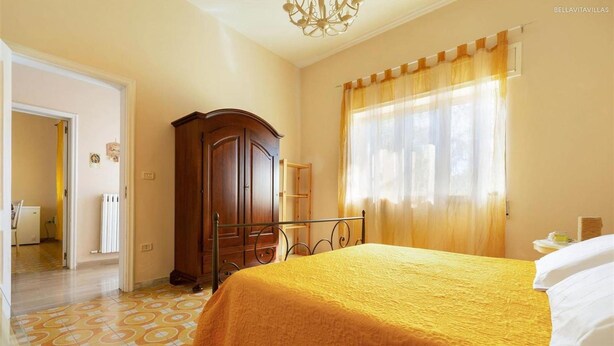 Ein Schlafzimmer mit Bett, Kleiderschrank und einem fenster mit Vorhängen.