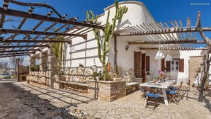 Eine Terrasse mit Esstisch, umgeben von Steinmauern und Kakteen.