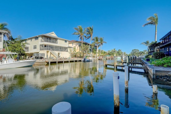 A marina with boats docked, a clear blue sky, and buildings with balconies and palm trees. - B-2 - Waterfront Condo Near Naples Bay & Beaches (Naples)