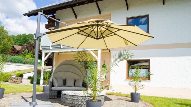 Un espace patio agrémenté d’un grand parasol, de meubles d’extérieur et de plantes en pot.