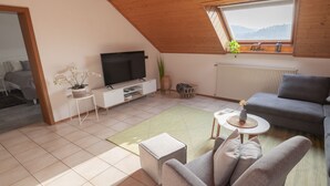 Un salon moderne avec un téléviseur, un canapé et une petite table.