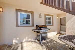 A patio area with a grill, two windows, and a door.