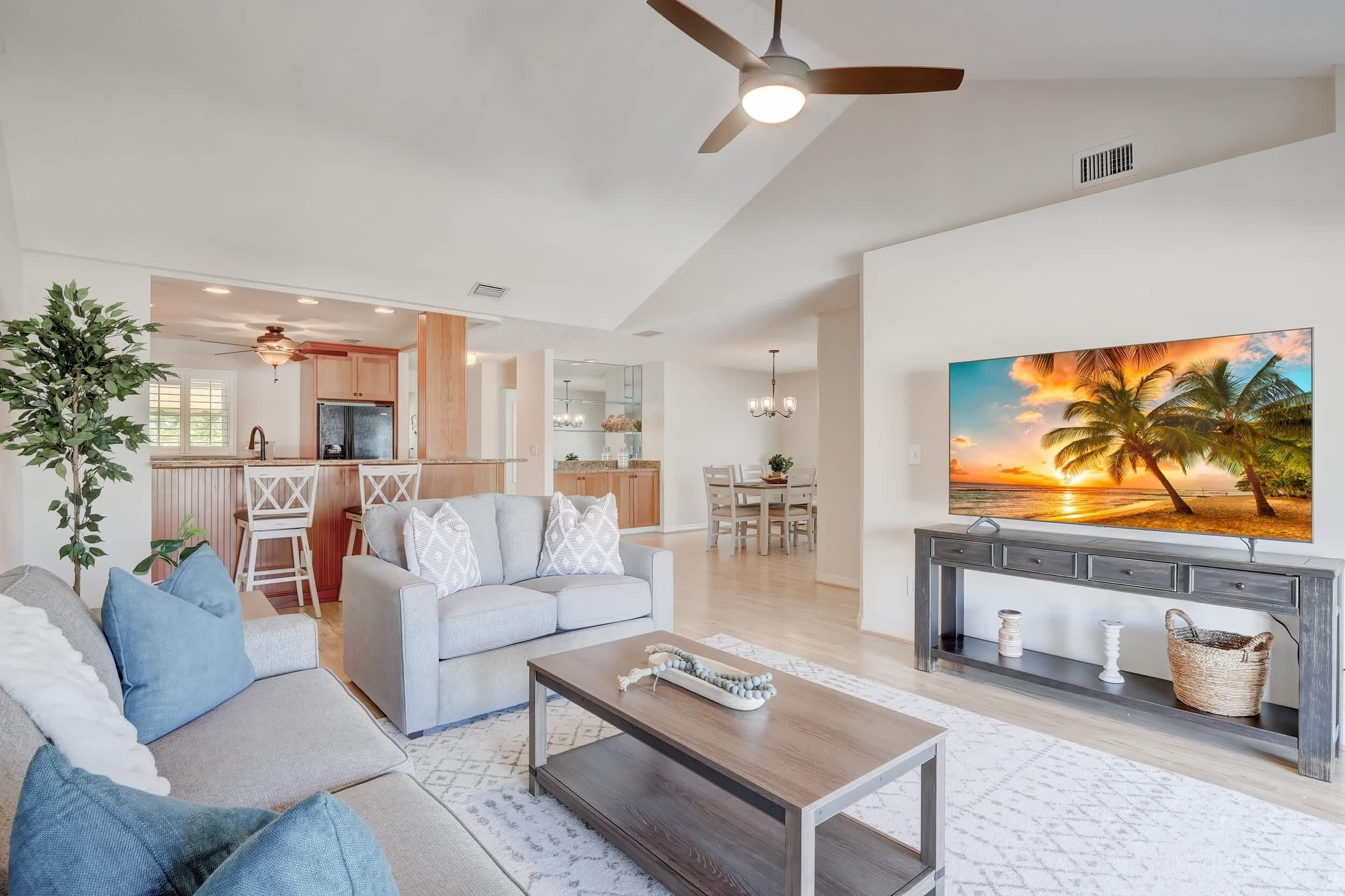 A spacious living area with a sofa, coffee table, and a painting of a sunset.