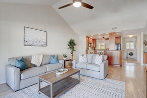 A modern living room with a sofa, coffee table, and a painting on the wall.