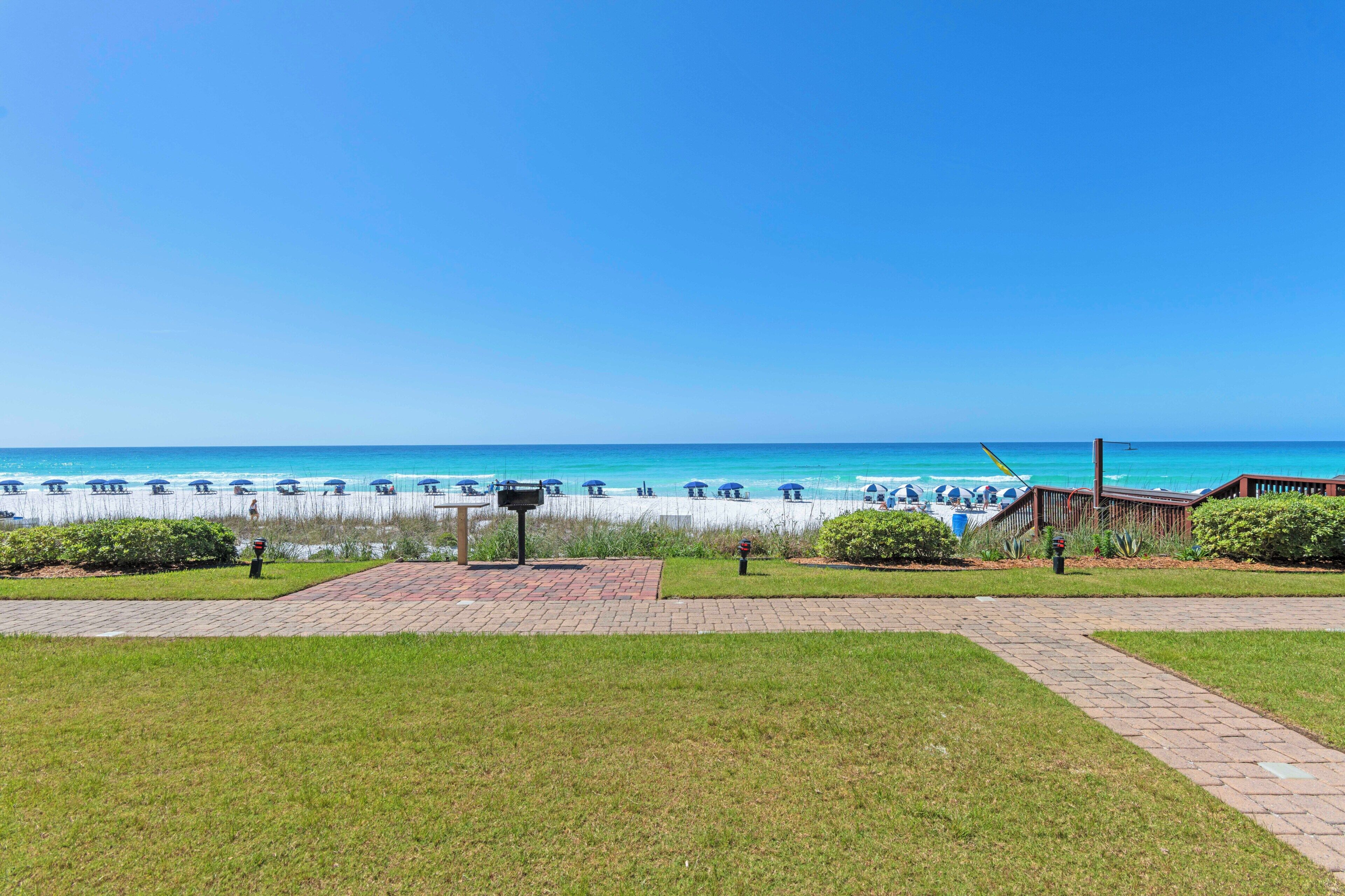 A beach view with a pathway leading to beach umbrellas and lounge chairs.
