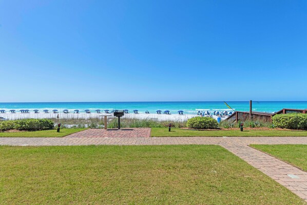 A beach view with a pathway leading to beach umbrellas and lounge chairs. - NEWLY UPDATED GROUND FLOOR BEACHFRONT CONDO AT THE CORAL REEF CLUB (Destin)