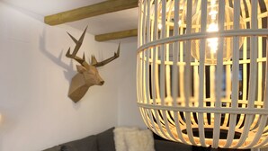 Een moderne woonkamer met een grijze bank, een decoratieve gewei van een hert aan de muur en een bijzondere hanglamp.
