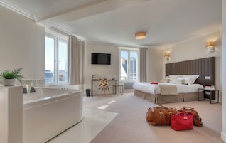 Habitación de hotel moderna con una cama grande, un escritorio, un televisor de pantalla plana y una bañera.