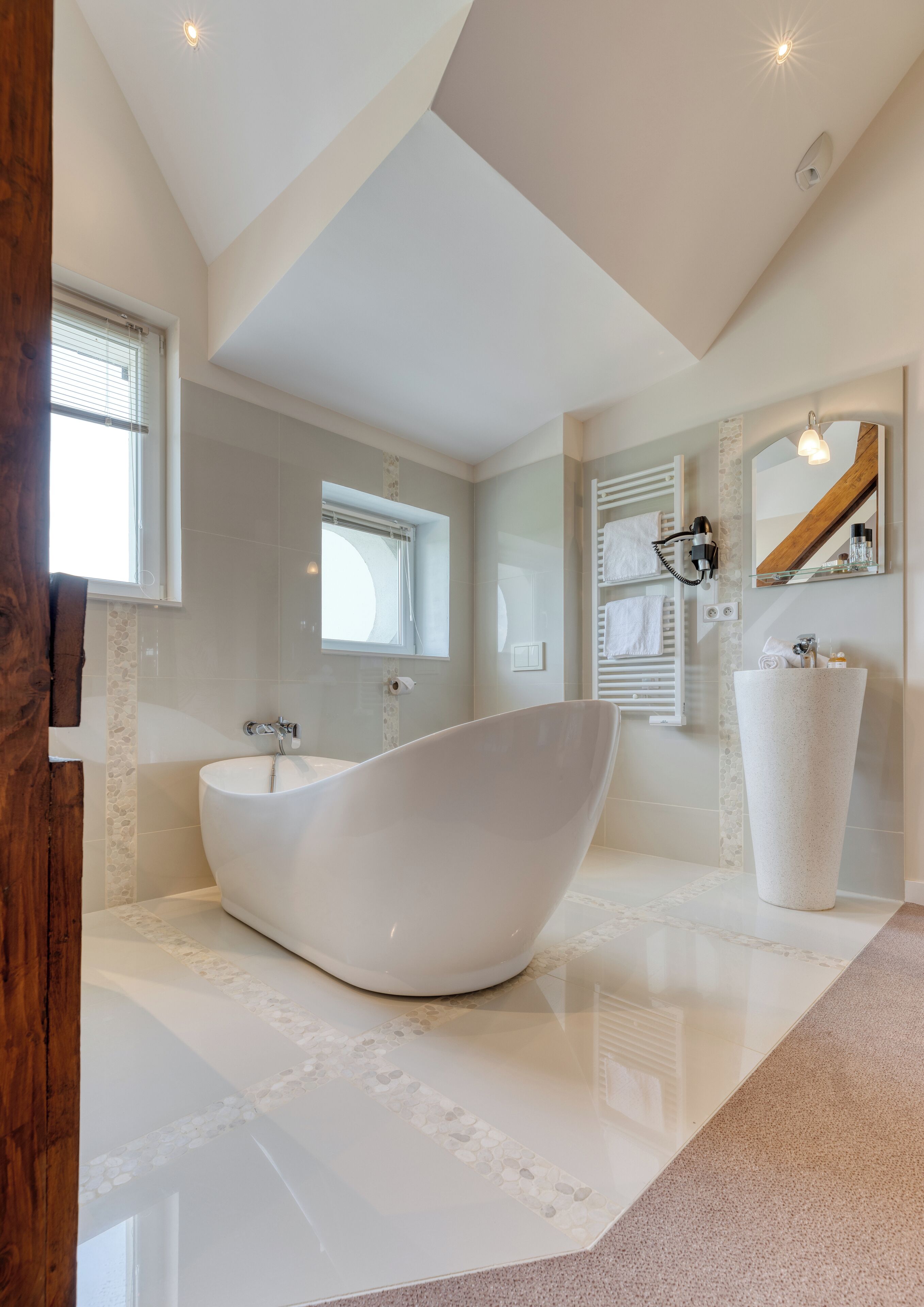 A modern bathroom with a freestanding bathtub, a large mirror, and a built-in sink.