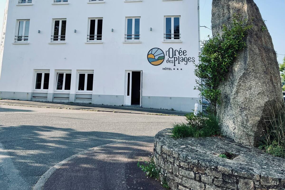 A white hotel with multiple windows and a sign reading "Oure des Plages HOTEL".