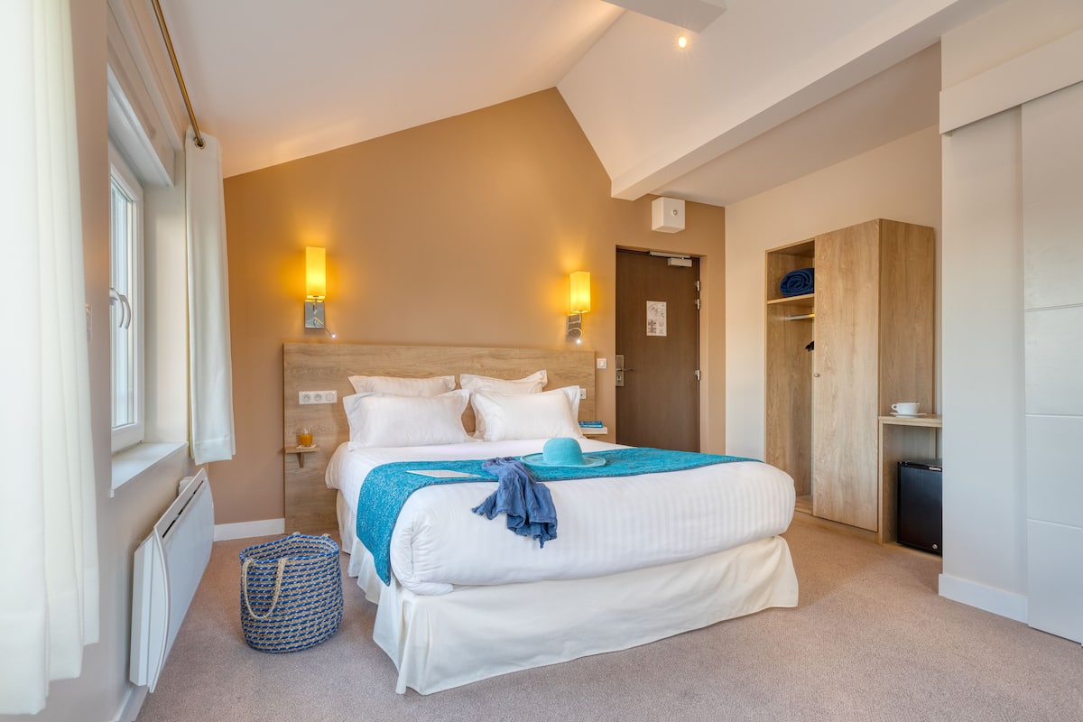 A bedroom with a large bed, bedside lamps, a wooden wardrobe, and a radiator.
