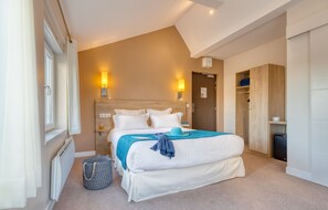 A bedroom with a large bed, bedside lamps, a wooden wardrobe, and a radiator.