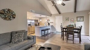 A modern living room with a gray sofa, a coffee table, and a dining area with wooden chairs and a table. - Amazing Views - Peaceful surroundings - Pets OK with fee (Ruidoso)