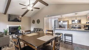 A modern kitchen with a central island, a dining area with a wooden table and chairs, and a living room with a sofa and fireplace. - Amazing Views - Peaceful surroundings - Pets OK with fee (Ruidoso)