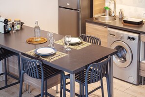 Una cucina moderna con un tavolo da pranzo per due persone, una lavatrice e un frigorifero in acciaio inossidabile.