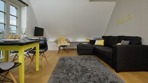 En moderne stue med spiseplads, en sort sofa og en grå måtte.