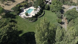 An aerial view of a property with a swimming pool, surrounded by a well-maintained lawn and trees. - Cortijo for 6 with Large Swimming Pool in 36 Acres of Land in Sierra Nevada Park (Granada)