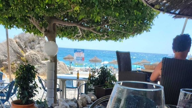 A seafood dish on a table with a glass of white wine, overlooking a beach with umbrellas and chairs. - Cortijo for 6 with Large Swimming Pool in 36 Acres of Land in Sierra Nevada Park (Granada)
