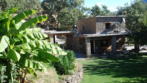 A rustic stone house with a satellite dish, surrounded by lush greenery and a well-maintained lawn. - Cortijo for 6 with Large Swimming Pool in 36 Acres of Land in Sierra Nevada Park (Granada)