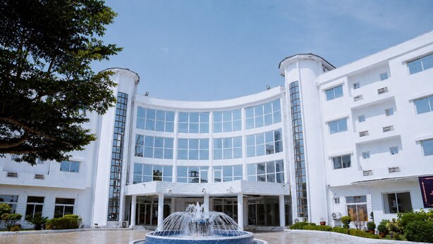 A modern building with a central fountain, large windows, and a symmetrical design.