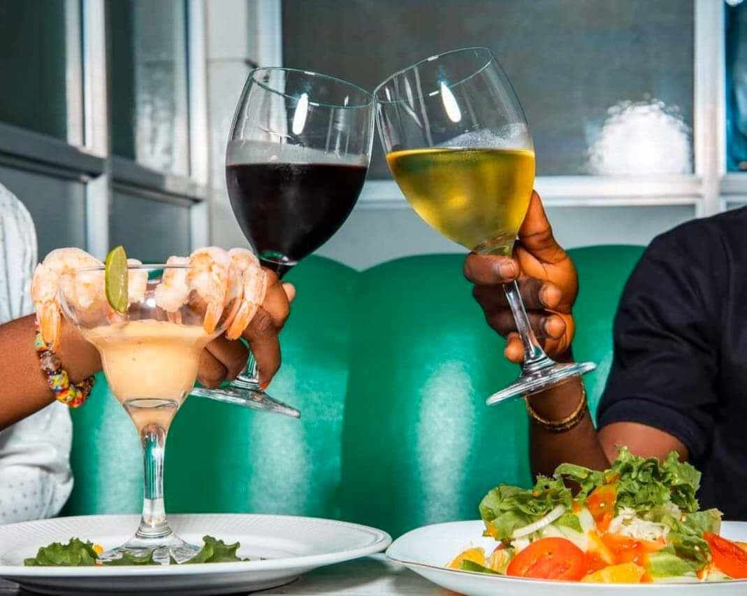 A dining table with two drinks, one in a martini glass and one in a wine glass, and a plate of salad.