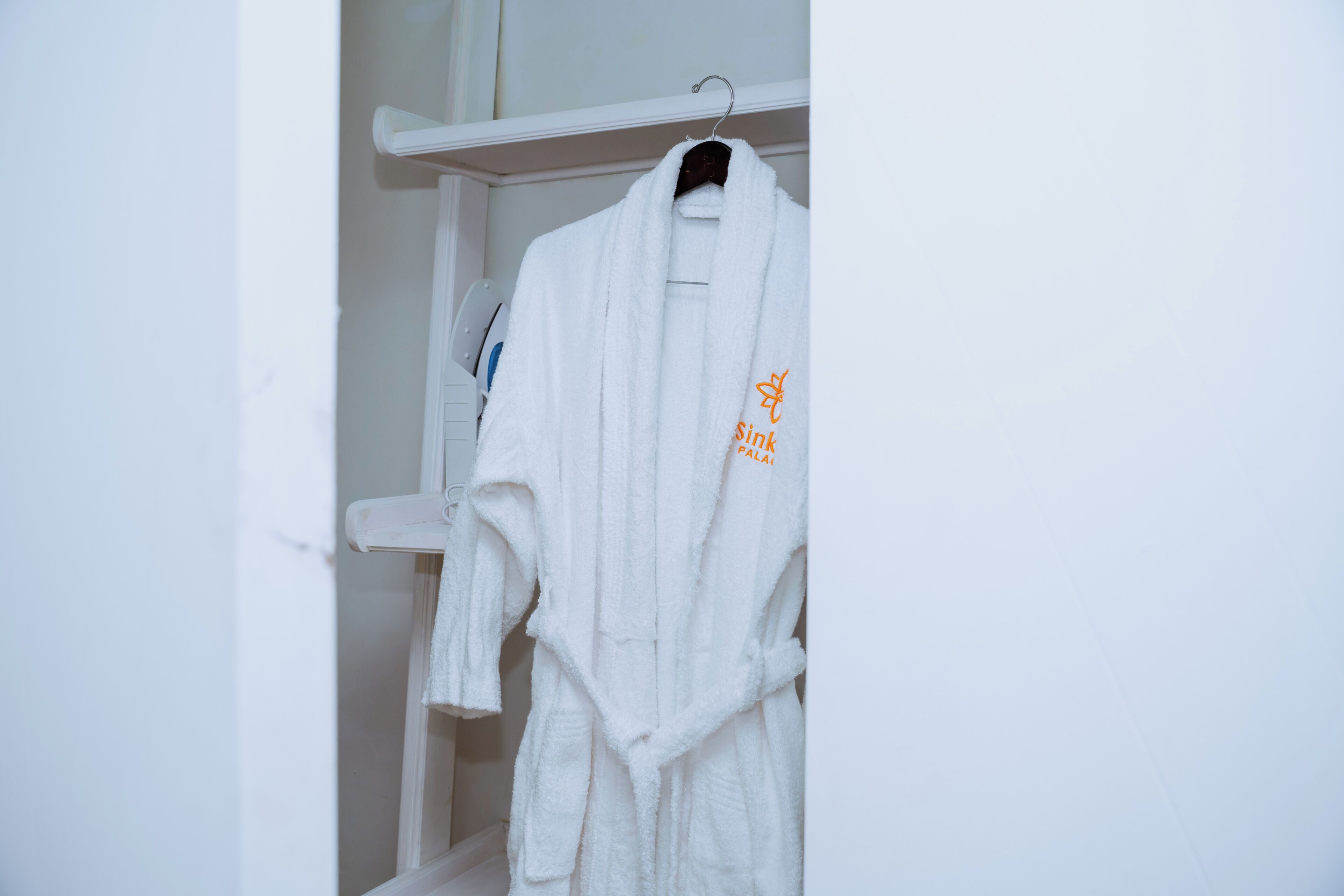 A white robe hanging on a white wall-mounted rack in a bathroom.