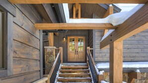 A wooden staircase leading to a door with a stone wall behind it. - Custom Mountain Retreat – Hot Tub & Summer Views (Keystone)