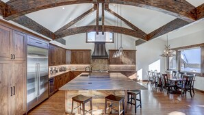 A spacious kitchen with a large island, wooden beams, and a view to the outside. - Custom Mountain Retreat – Hot Tub & Summer Views (Keystone)
