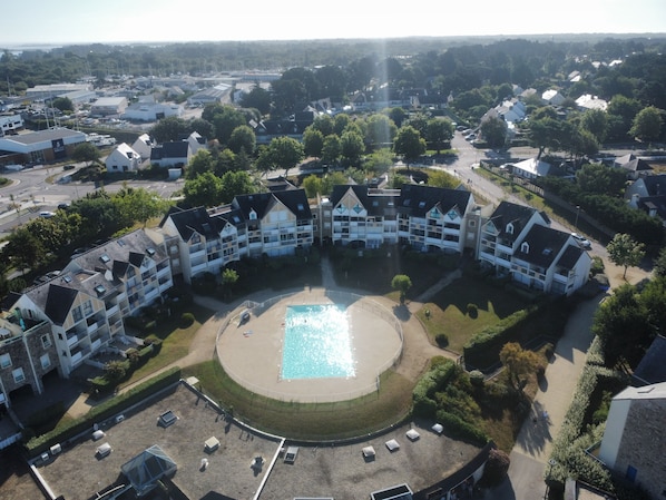 An aerial view of a residential area with a central swimming pool surrounded by multi-story houses. - RHUYS PENINSULA, Port of Crouesty - 2-room apartment, 39 m², 4 guests (Arzon)