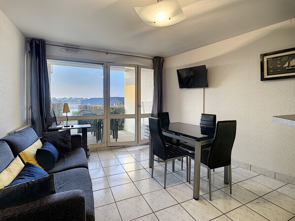 A modern living room with a sofa, dining table, chairs, and a TV. - RHUYS PENINSULA, Port of Crouesty - 2-room apartment, 39 m², 4 guests (Arzon)