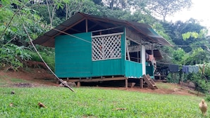 A green house with a sloped roof, a lattice window, and a small porch. - Bribri Ù sule (Bratsi)