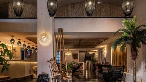 A spacious lobby with a reception desk, seating area, and a large plant. - Indigo Inn Casa - Adults Only (Hersonissos)
