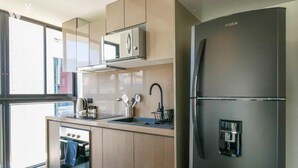 A modern kitchen with a built-in oven, a coffee machine, and a refrigerator.