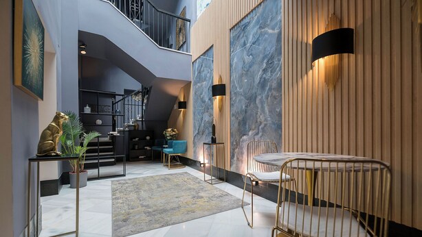 A modern interior with a staircase, a dining area with a table and chairs, and a decorative sculpture. - Boutique Suites (Arcos de la Frontera)