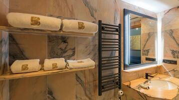 A bathroom with marble walls, a black towel rack, a mirror, and a sink.