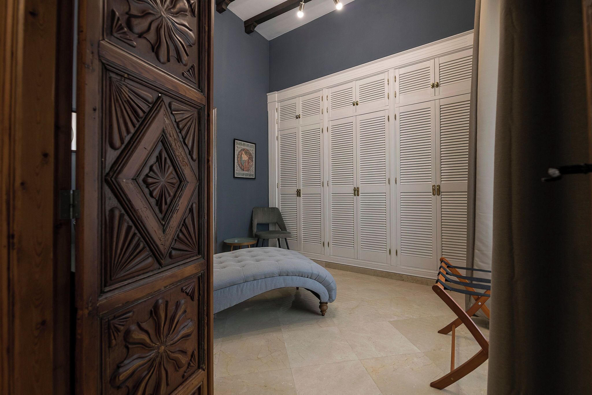 Un dormitorio con cama, armario, silla y banco.