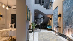 A spacious interior with a staircase, a dining area with a table and chairs, and a living area with seating and decor. - Boutique Suites (Arcos de la Frontera)