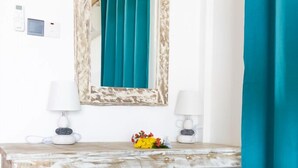 A bathroom with a marble vanity, a small stool, a mirror, and a teal shower curtain. - The Habitat Sesel (Mahé Island)
