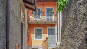 Un estrecho callejón que conduce a un edificio con un balcón, una puerta y una ventana con persianas.