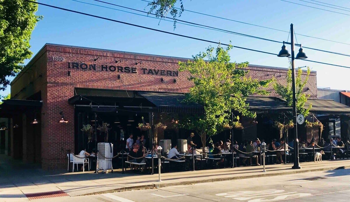 An exterior of the Iron Horse Tavern with outdoor seating and a brick facade.