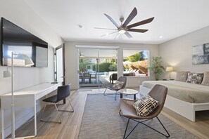 A modern bedroom with a bed, desk, and seating area.