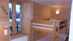 Ein Zimmer in einer Holzhütte mit Etagenbetten, einem Fenster und einer Wandleuchte.